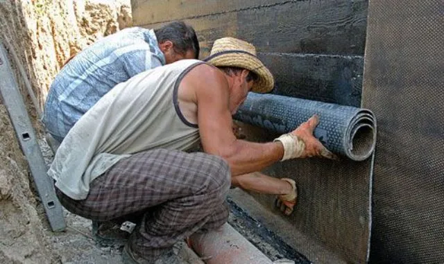 Строители оклеивают стену листами гидроизоляционного материала