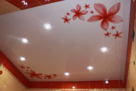 Красные цветы на натяжном полотне гармонично сочетаются с цветом кафельной плитки на стенах в ванной