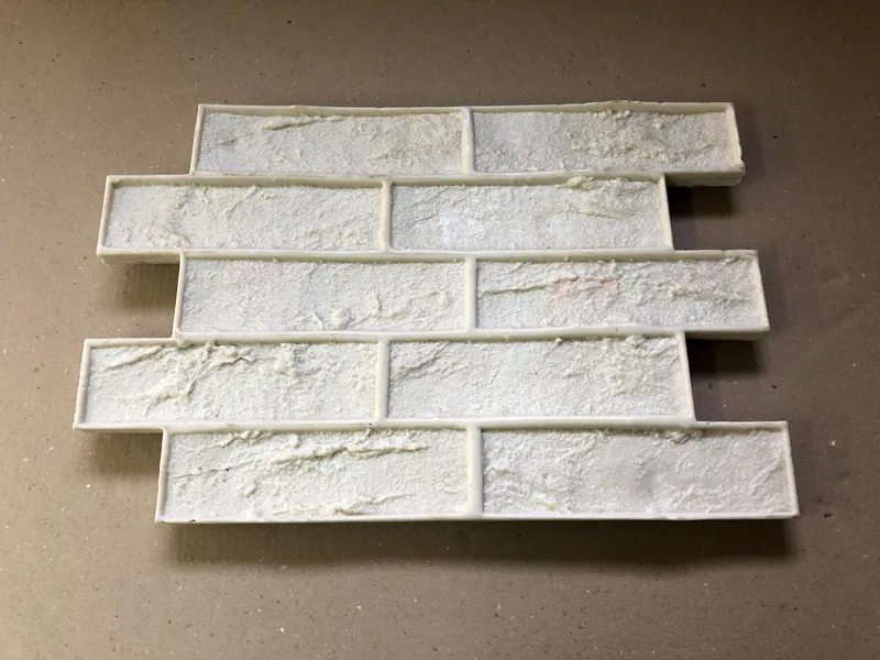 Раствор на стене уплотняется, выравнивается, затем к нему прикладывают штамп. А вот по штампу бьют специальным молоточком или рукой